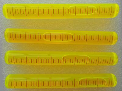 There are four yellow plastic tubular level vials with scale on them.